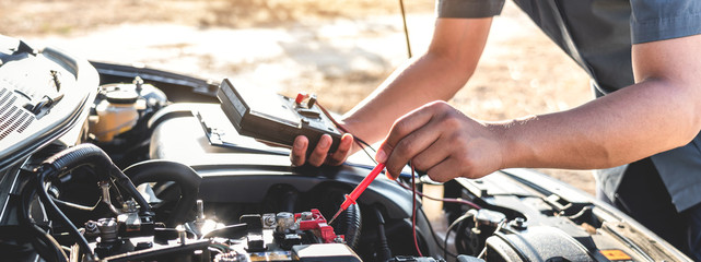 Mechanic repairman checking engine automotive in auto repair service and using digital multimeter...