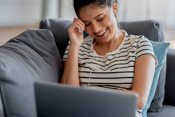 Young Asian woman is watching something funny on a laptop.