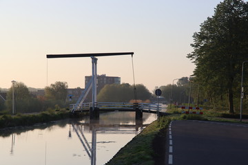 Wooden drawbridge called Witte Brug during sunrise in the town of Nieuwerkerk aan den IJssel over the ring canal of the Zuidplaspolder Nederland