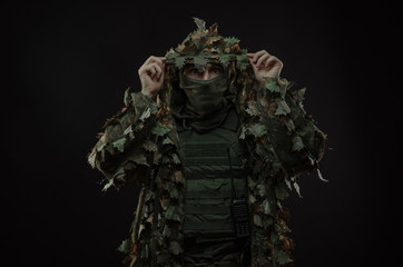 sniper in a camouflage suit poncho with a gun