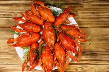 Boiled crayfish in plate on wooden table. Top view