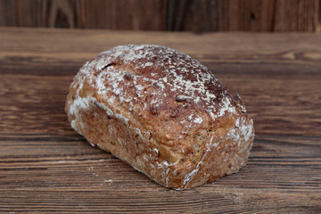 View of fresh bread sprinkled with flour. A freshly baked loaf on a wooden, brown, rustic table.