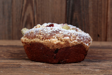 Side view, close-up of home-made fresh yeast cake stuffed with fruit, rhubarb on a wooden, brown, rustic table.
