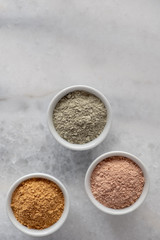 Set of different cosmetic clay mud powders on white background