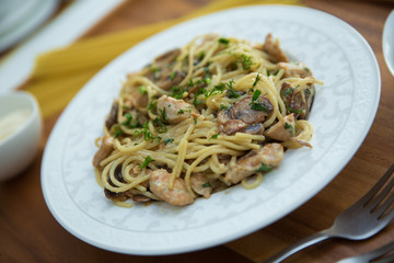 Mushrooms over spaghetti . Raw spaghetti pasta inside a bowl . Black pepper, Mayonnaise inside a bowl. Forks . Uncooked spaghetti . Delicious spaghetti wooden tray .