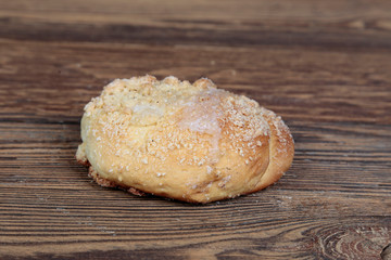 View, close-up of a fresh, homemade bread roll with sprinkles on a wooden, brown, rustic table.