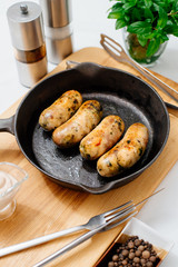 Fried chicken sausages and sweet peppers on a cast-iron frying pan