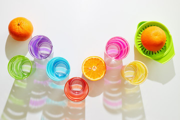 Colourful glasses waiting to be filled with orange fruit juice