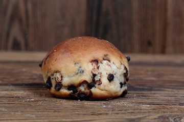 Side view, close-up of a fresh, homemade bread roll with filling on a wooden, brown, rustic table.