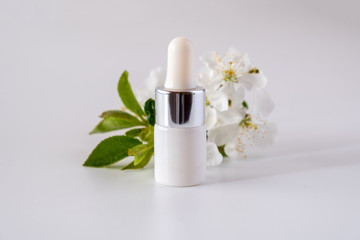 Obraz na płótnie Canvas White cosmetic skincare dropper bottle packaging cherry blossoms flowers on white background