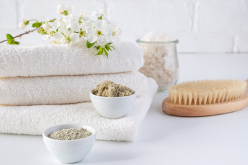 Set of different cosmetic clay mud powders on white background. Ingredients for homemade facial and body mask or scrub and fresh sprig of flowering cherry . Spa and bodycare concept.