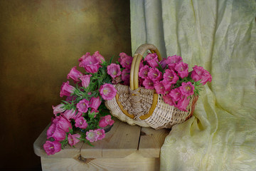 Bouquet of pink bells in a basket on the table on a brown background