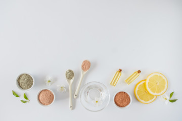 Set of different cosmetic clay mud powders on white background. Ingredients for homemade facial and body mask or scrub and fresh sprig of flowering cherry . Spa and bodycare concept.