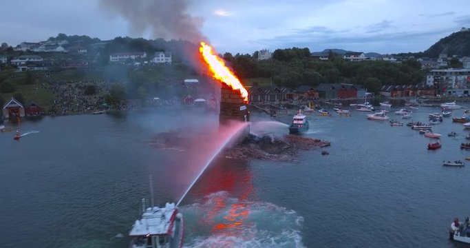 Unbelievably beautiful, cinematic, low level, forward flying drone footage that reveals the biggest bonfire event on Earth and the small boats gathering around it near Alesund, Norway at dusk.