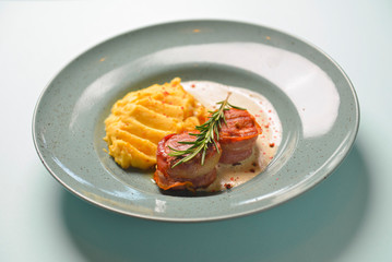 Beef meat pieces with mashed potato, onion gravy and spices. Served on a blue plate over blue mint background.