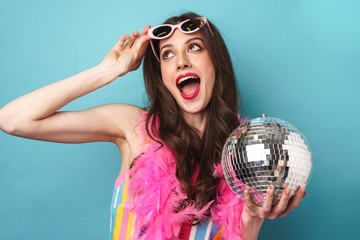 Photo of joyful young woman smiling while posing with disco ball