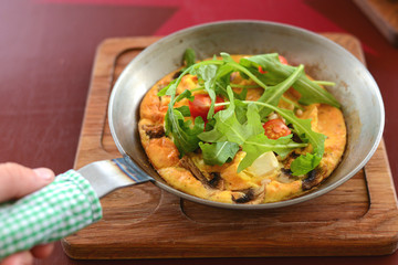 English breakfast - fried egg, beans, tomatoes, mushrooms, seeds served in a pan over rustic wooden board.