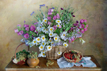 Still life with wildflowers in a basket, ripe berry
