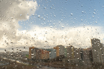 Drops of water or rain drops on window glass with blur buildings background.
