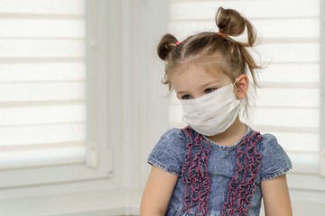 little girl in a disposable mask showing stop gesture with palm looking straight at camera