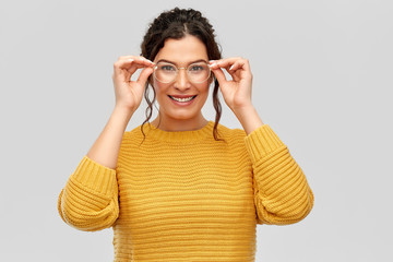 vision, accessory and people concept - portrait of happy smiling young woman with pierced nose in glasses over grey background