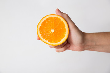 Person holding half of orange fruit isolated on white background. Cropped shot, closeup, side view. Healthy nutrition or organic food concept