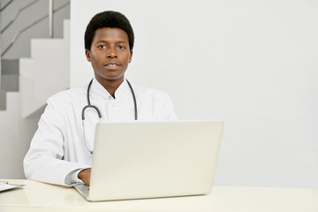 African doctor using laptop on reception.