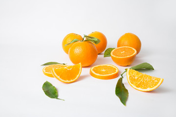Ripe whole oranges with green leaves and sliced parts isolated on white background. Closeup, side view. Natural vitamin or organic food concept