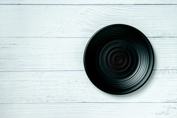 An empty plate resting on a white wooden floor.