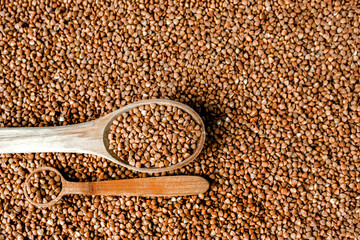 Buckwheat texture. Wooden spoon of roasted buckwheat on buckwheat groat jar background, gluten free ancient grain for healthy diet, selective focus. Coronavirus food supplies. background. top view.