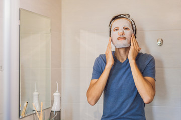 Young man doing facial mask sheet. Beauty and Skin Care Concept