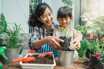 happy excited mother and her daughter gardening together plants some flower at home