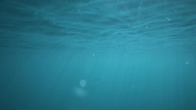 Morning light shining through the surface of perfect calming blue ocean, slowmo