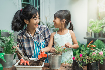 happy excited mother and her daughter gardening together plants some flower at home