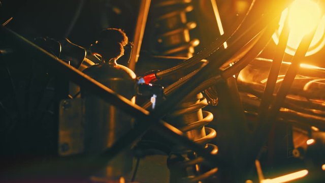 Close-up details of car engine on background of bright light. Stock footage. Yellow light illuminates dark shapes of parts with springs and cylinders for car