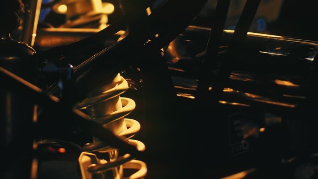 Close-up details of car engine on background of bright light. Stock footage. Yellow light illuminates dark shapes of parts with springs and cylinders for car