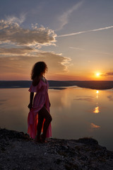 Model posing in dress on background of sunset near lake.