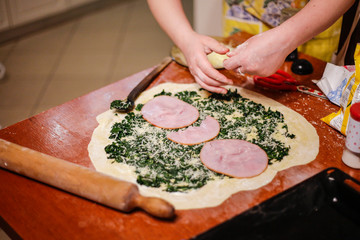 Homemade bread, kneading dough, pizza, spinach, mushrooms and ham
(Prosciutto) wraps. Girl cooking food with baking ingredients.