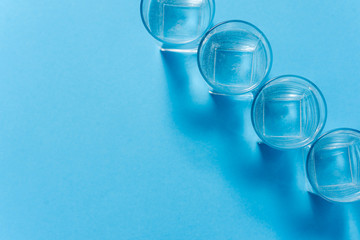 Line of glasses, a glass with water, on a light blue background. Difference concept. Equality concept.