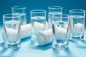 Water filters. Carbon cartridges and glasses on a blue background. Household filtration system.