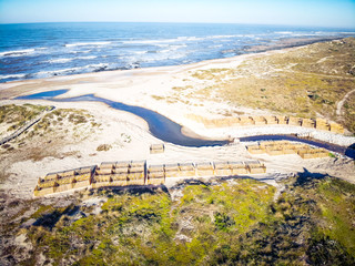 Aerial view of dune fencing to control wind erosion and encourage dune stability. Stream flowing...