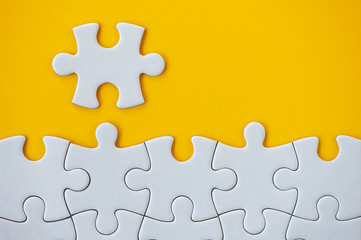 Puzzle pieces on orange background. White square puzzle pieces grid. Business background. Copy space for text, top view, close up.