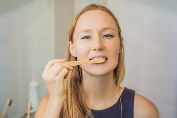 Young and caucasian woman brushing her teeth with a bamboo toothbrush