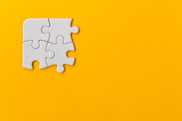 Puzzle pieces on orange background. Quaternary piece flat puzzle. Business background. Copy space for text, top view.