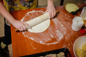 Homemade bread, kneading dough, pizza, spinach, mushrooms and ham
(Prosciutto) wraps. Girl cooking food with baking ingredients.