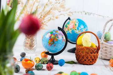 Fototapeta na wymiar Easter eggs and globe on a white wooden background