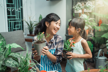 beautiful mother and daugther smiling to camera while gardening and planting some plants at home