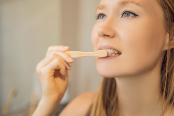 Young and caucasian woman brushing her teeth with a bamboo toothbrush