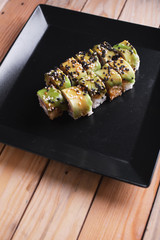 Salmon sushi on a square black plate on a dark wooden background