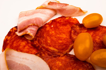 Slices of sausage and bacon and tomatoes on a white background. Close up.